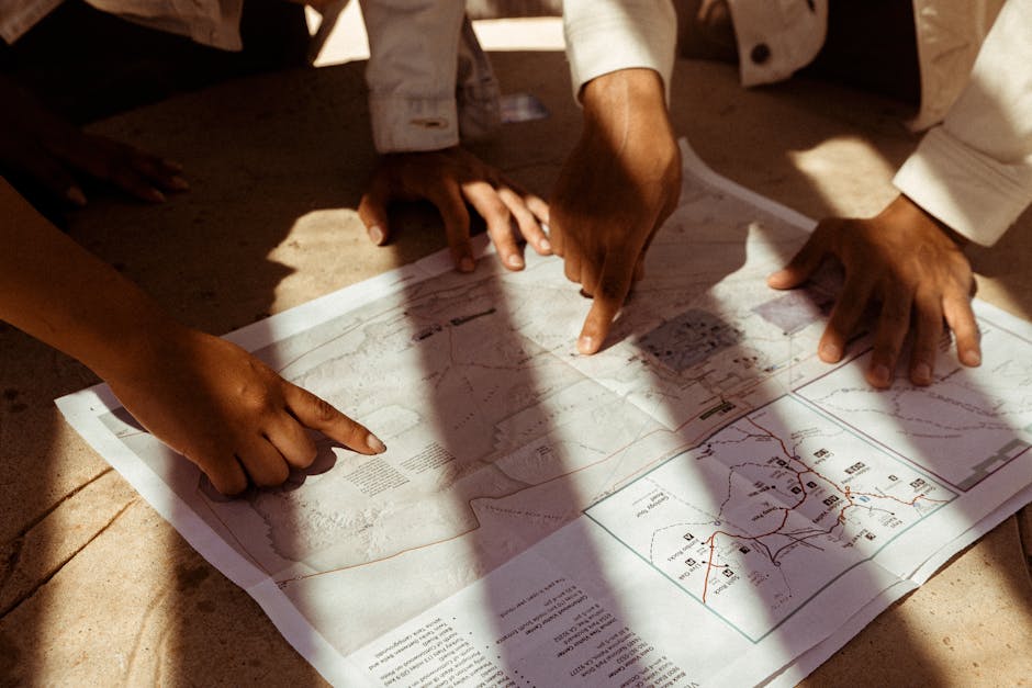 Group of hands pointing at a detailed map, planning an adventure trip in sunlight.