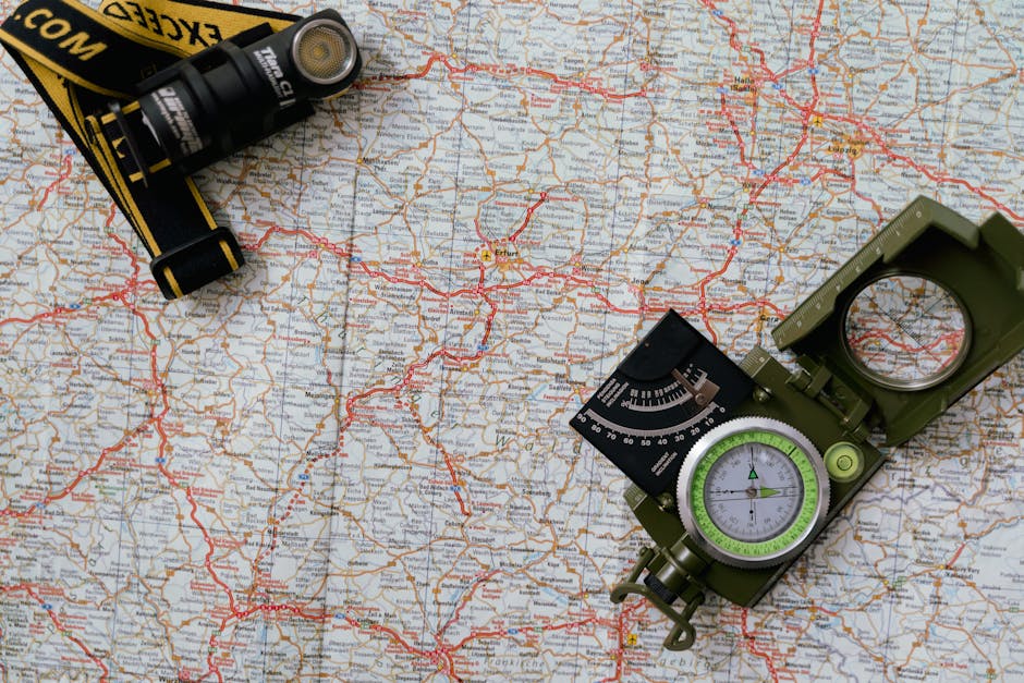 Overhead view of a map with a compass and flashlight showing navigation tools.